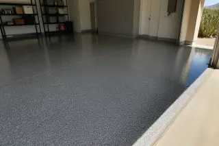 High-gloss speckled epoxy garage floor with sharp shadows and prickly pear cacti visible in Phoenix, AZ.