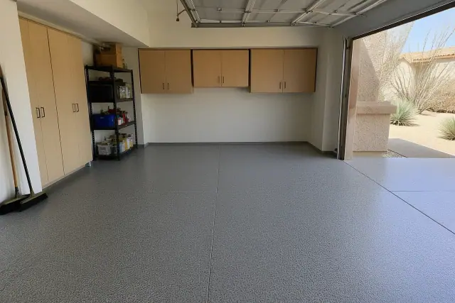 Residential garage with gray flake flooring, storage cabinets, and a view of desert landscaping in Phoenix, AZ.