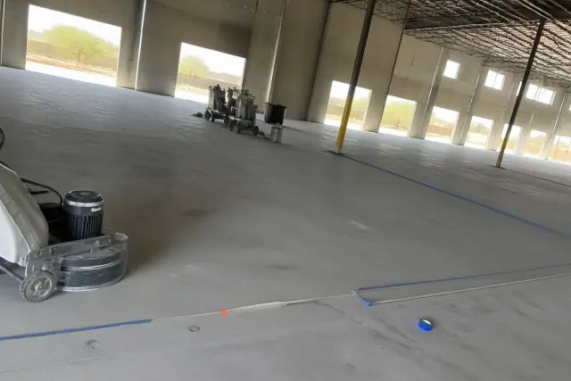 Raw concrete floor with industrial grinders in a warehouse awaiting epoxy coating in Phoenix, AZ.