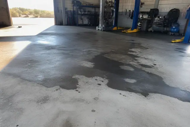 Oil residue and curing compound stains on a concrete floor in an automotive service bay in Phoenix, AZ.