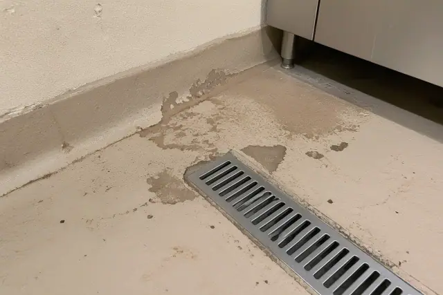 Peeling floor coating near a drain in a professional kitchen in Phoenix, AZ.