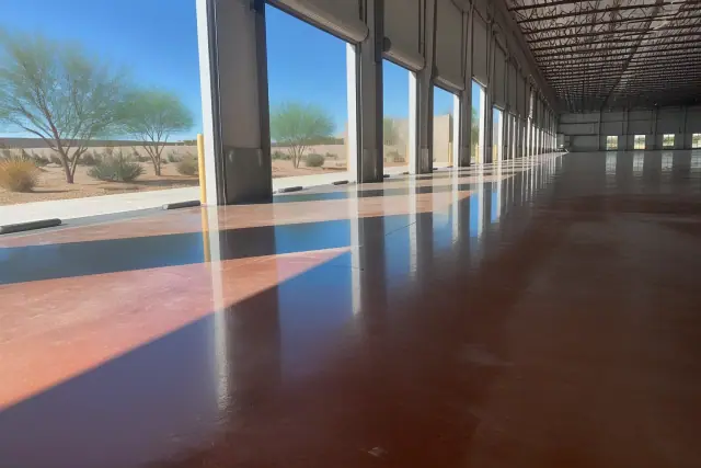 Polished and stained concrete flooring inside a logistics building in Phoenix, AZ, with desert light from open bay doors.