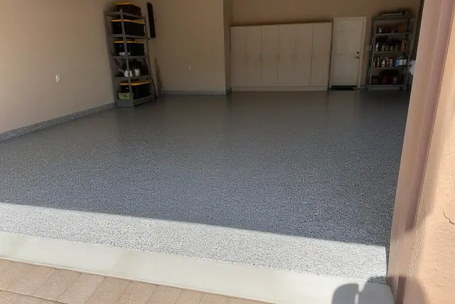 Gray epoxy flake garage floor with a glossy finish and beige stucco walls in a Phoenix, AZ home.