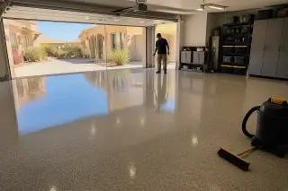 Technician inspecting a finished epoxy floor in a Phoenix, AZ garage with desert views through the open door.