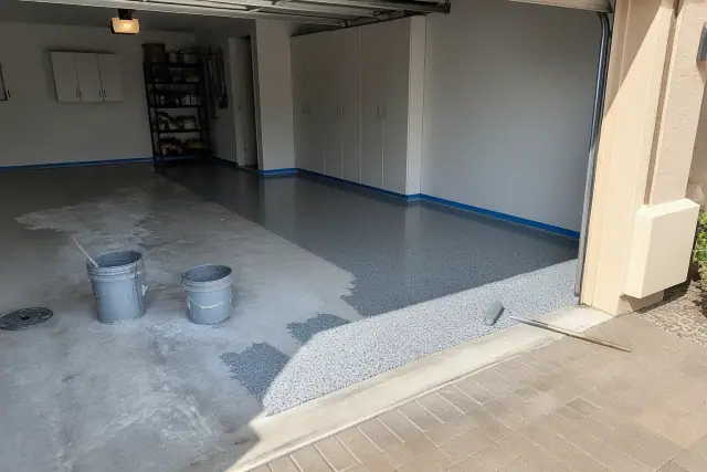 Residential epoxy flooring in progress inside a garage with tools and supplies in Glendale, AZ.