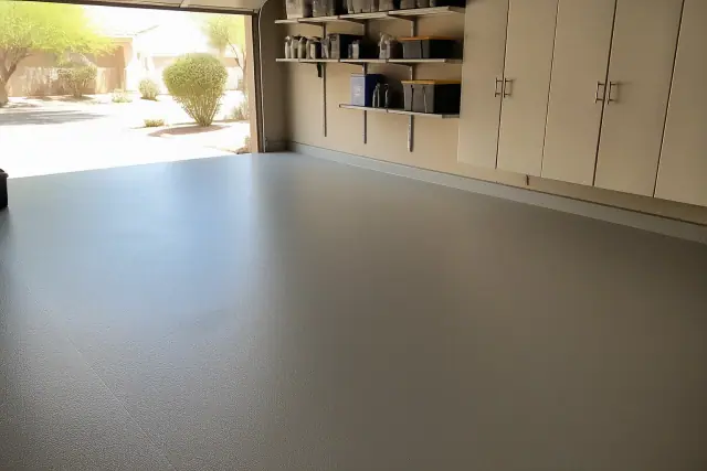 Smooth solid-color epoxy floor in a residential garage with storage cabinets in Phoenix, AZ.