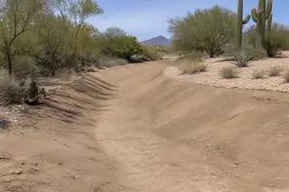 Finished drainage swale with smooth soil slopes and desert earth texture at a construction site in Phoenix, AZ.