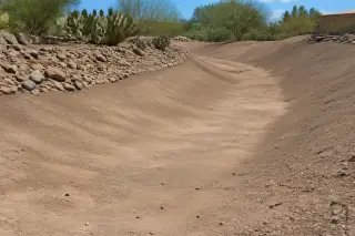 Shallow sloping drainage swale with smooth soil transitions and desert landscaping in Phoenix, AZ.