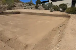 Smoothly graded dirt pad on a sloped desert site with harsh sunlight in Phoenix, AZ.