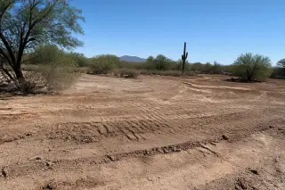 Leveled desert ground with cleared soil and subtle earth-moving tracks at a construction site in Phoenix, AZ.