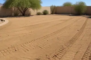 Compacted flat earth with soil roller tracks transitioning to desert landscaping at a Phoenix, AZ construction site.