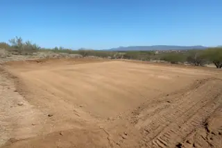 Leveled and compacted dirt pad on a sloped site prepared for construction in Phoenix, AZ.