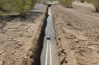 Backfilled narrow utility trench in rocky desert soil at a construction site in Phoenix, AZ.
