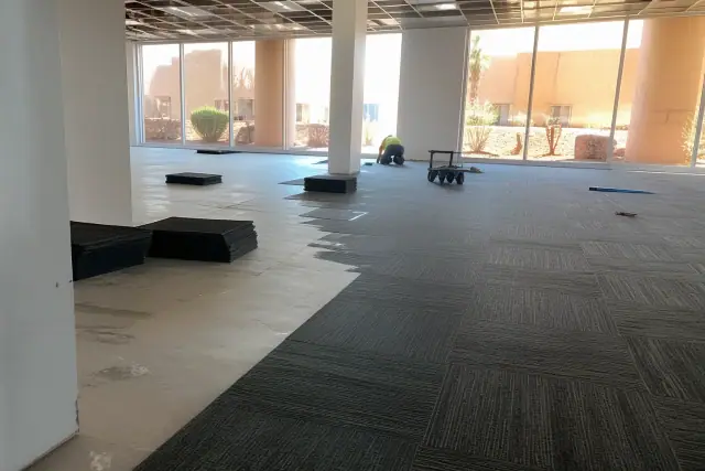 Worker installing carpet tiles during an office renovation in Phoenix, AZ.