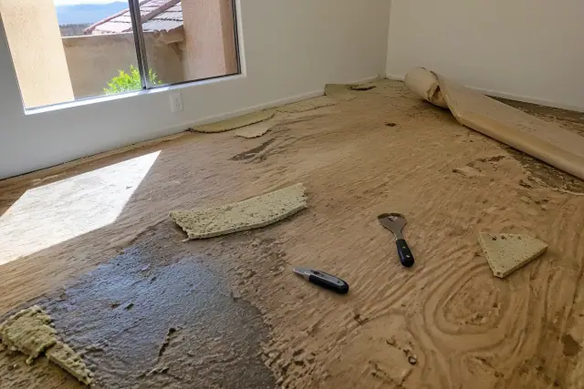 Technician removing old carpet to reveal the wooden subfloor during an installation in Chandler, AZ.