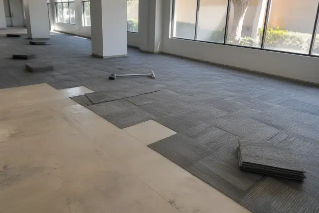 Carpet tile installation in an office workspace in Glendale, AZ with tools on the floor.