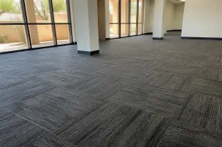 Close-up of carpet tile texture and seams in a sunlit Phoenix, AZ office workspace.