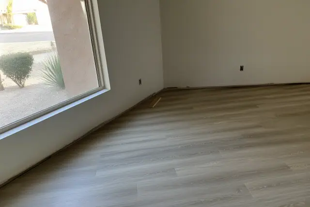 Click-lock laminate flooring installed in a Phoenix, AZ home with baseboard trim being fitted against the wall.