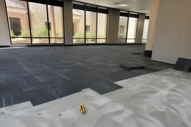 Carpet tiles being installed in an office workspace with tools and sunlight visible in Chandler, AZ.
