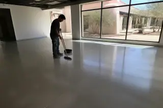 Technician cleaning polished concrete floors after a commercial renovation in a Phoenix, AZ office with desert views.