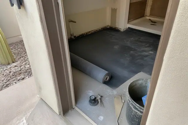 Contractor testing concrete slab moisture levels before installing an underlayment membrane in a Phoenix, AZ home.