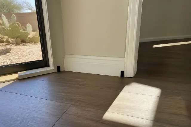 Expansion gap between laminate flooring and a wall with a spacer in a Phoenix, AZ home.