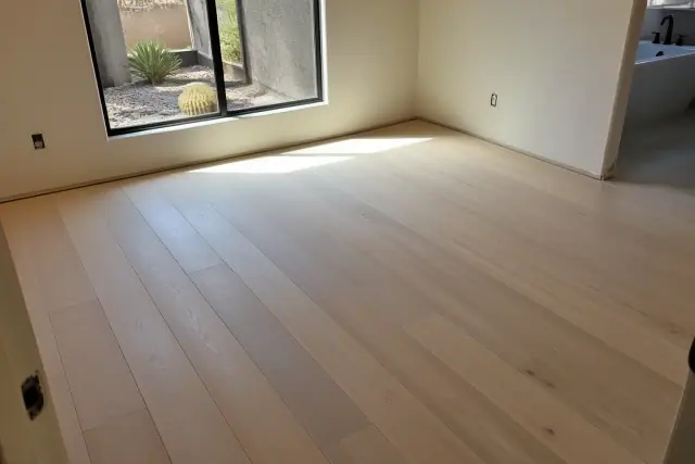 Newly installed engineered hardwood flooring in a bedroom with a view of a sun-drenched xeriscape in Phoenix, AZ.