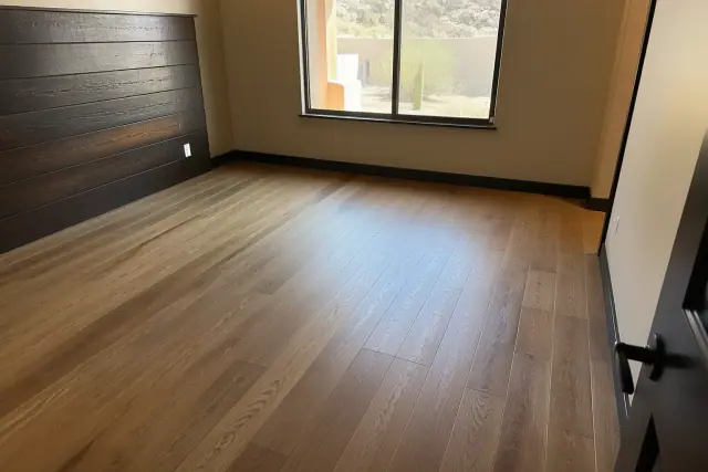 Installed engineered hardwood flooring in a Phoenix, AZ bedroom with a view of desert landscaping through the window.