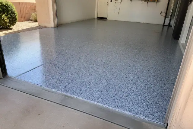 Completed epoxy floor with decorative flakes in a garage in Peoria, AZ, with desert landscaping visible outside.