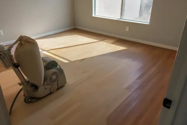 Industrial floor sander smoothing hardwood planks in a bedroom in Scottsdale, AZ.