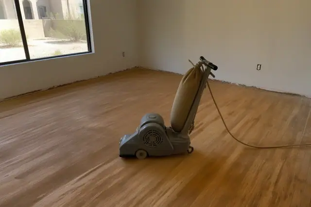 Industrial sander smoothing hardwood floor planks during a home restoration project in Peoria, AZ.