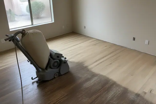 Industrial sander smoothing hardwood floor planks during a bedroom renovation in Mesa, AZ.