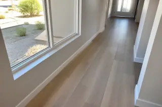 Staggered luxury vinyl planks in a residential hallway with a view of a xeriscaped yard in Phoenix, AZ.