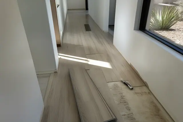 Contractor installing luxury vinyl planks in a staggered pattern in a hallway in Phoenix, AZ.