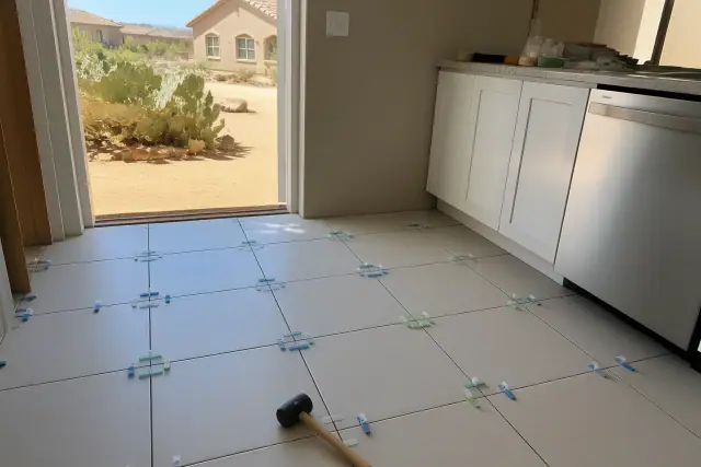 Ceramic tile installation with spacers on a kitchen floor in Peoria, AZ, with a desert landscape visible outside.