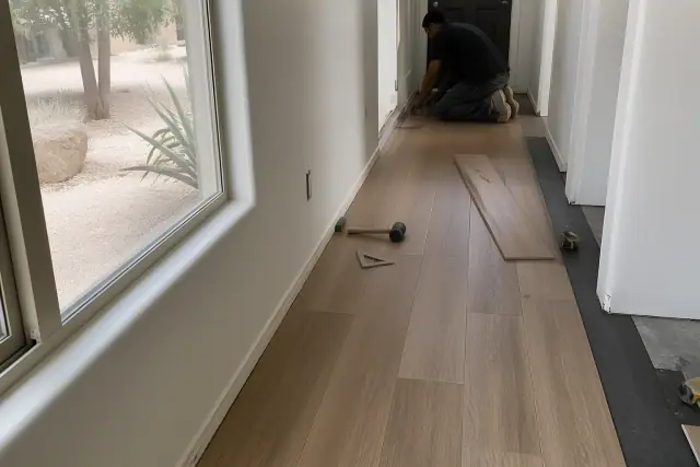 Worker installing luxury vinyl planks in a residential hallway in Chandler, AZ.