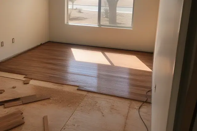 Partially installed hardwood floor with sawdust and unfinished edges in a bedroom in Phoenix, AZ.