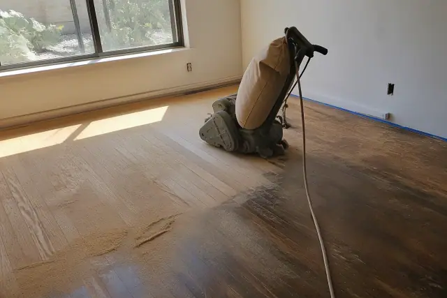 Industrial sander smoothing hardwood floors in a bedroom during a restoration project in Gilbert, AZ.