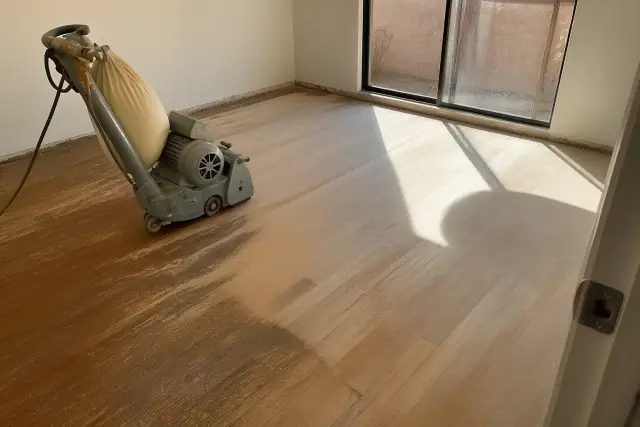 Industrial floor sander smoothing hardwood planks in a Phoenix, AZ bedroom during a flooring restoration.