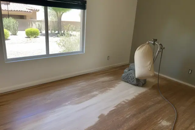 Industrial sander smoothing hardwood floor planks during a home restoration project in Peoria, AZ.