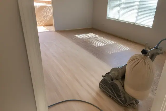 Industrial sander smoothing wood planks during a flooring restoration project in a bedroom in Phoenix, AZ.