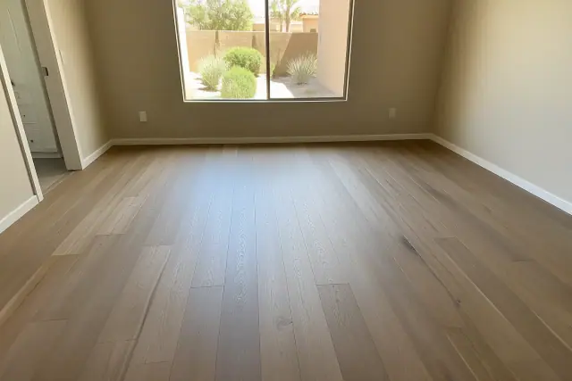 Freshly installed hardwood flooring in a bedroom in Gilbert, AZ, with a view of desert landscaping through the window.