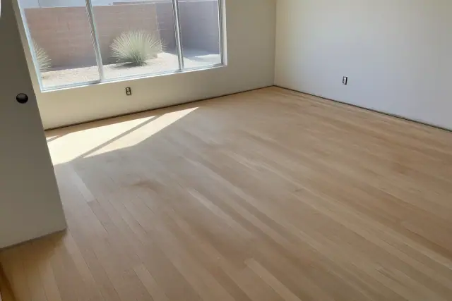 Hardwood flooring with visible wood grain and sawdust during a restoration project in Avondale, AZ.