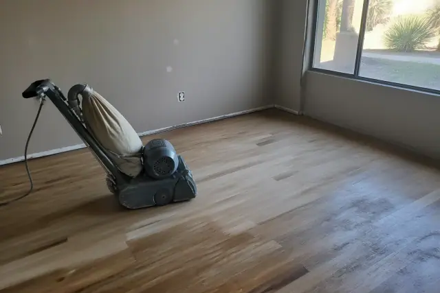 Industrial sander smoothing hardwood bedroom flooring during a restoration project in Peoria, AZ.