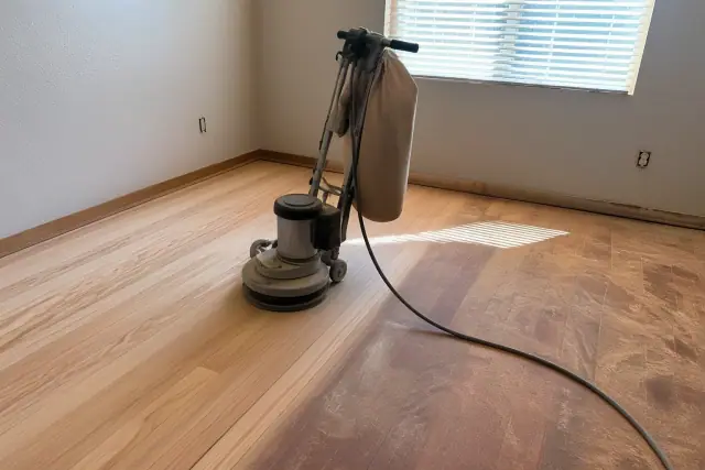 Industrial floor sander smoothing wood planks during a flooring restoration project in a bedroom in Phoenix, AZ.