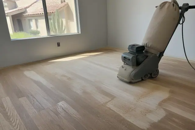 Industrial sander smoothing hardwood flooring in a Glendale, AZ bedroom during a home renovation.
