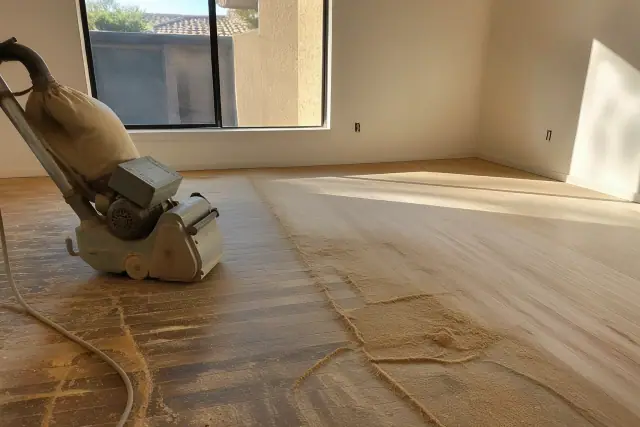 Industrial sander smoothing hardwood bedroom flooring during a restoration project in Goodyear, AZ.