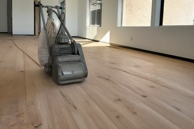 Industrial drum sander smoothing raw oak planks during a hardwood flooring restoration project in Phoenix, AZ.