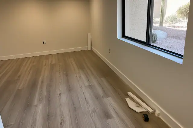 Newly installed laminate flooring and decorative baseboards in a Glendale, AZ basement.
