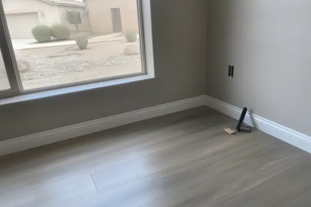 Installed laminate flooring with mitered baseboard trim in a residential home in Avondale, AZ.